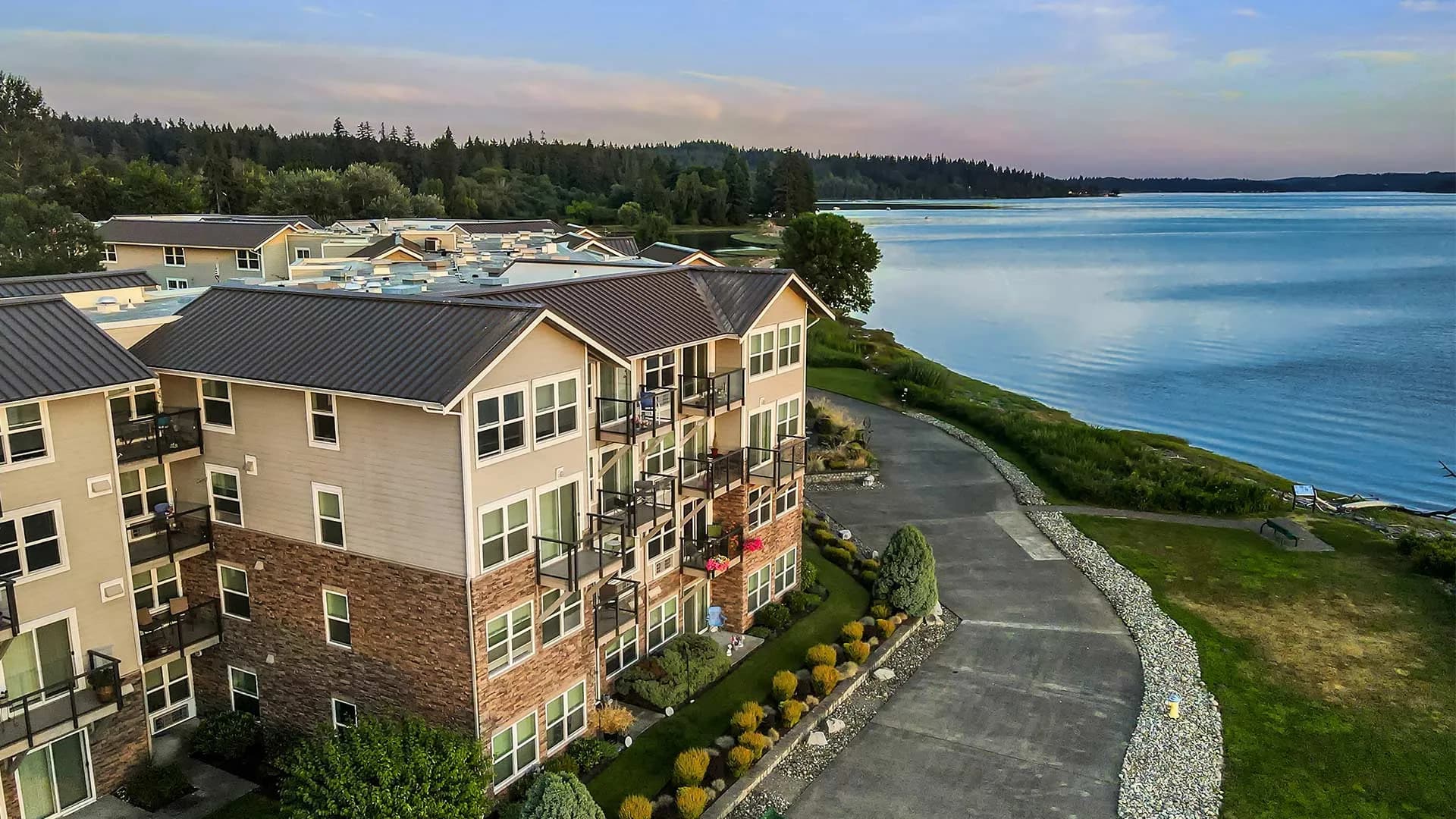 Aerial view of a lakeside residential community with wooded shoreline